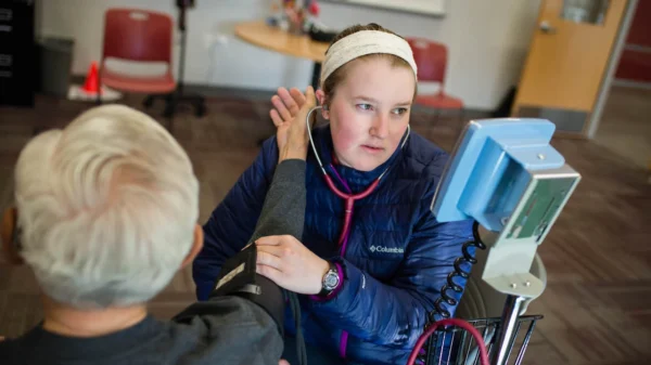 A student takes a community member's blood pressure.