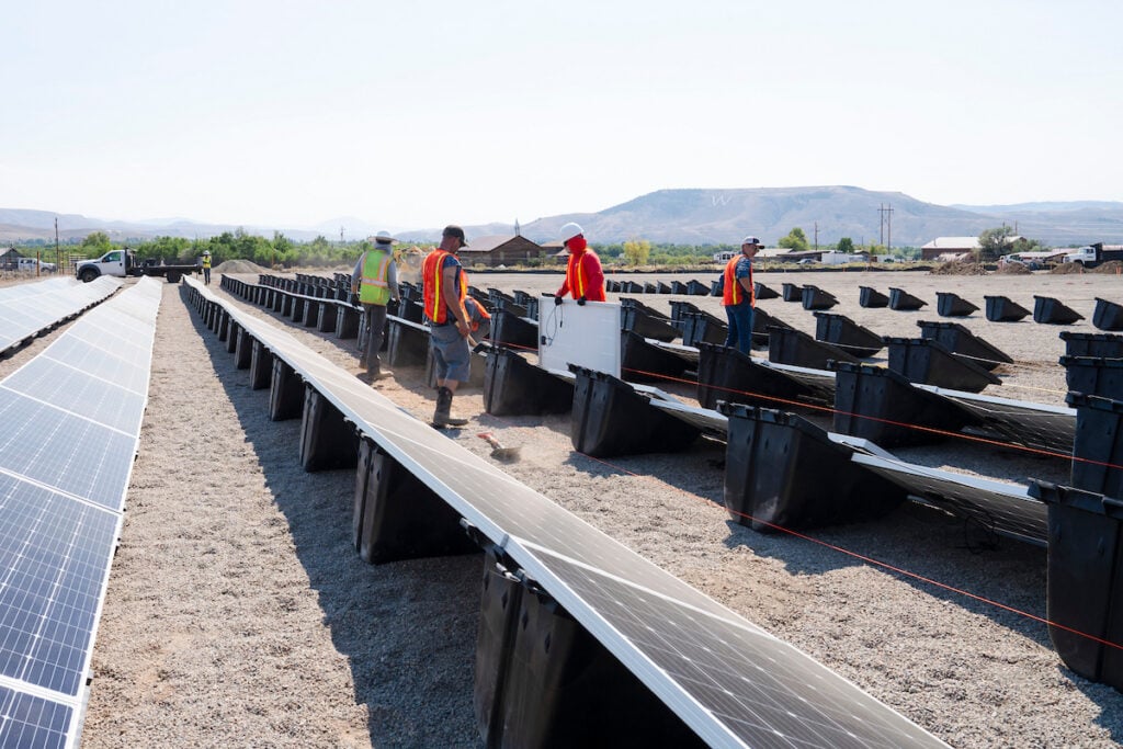 A Western student helps other employees mount a solar panel to Powerfield Energy's PowerRacks while helping build a solar array in Gunnison.