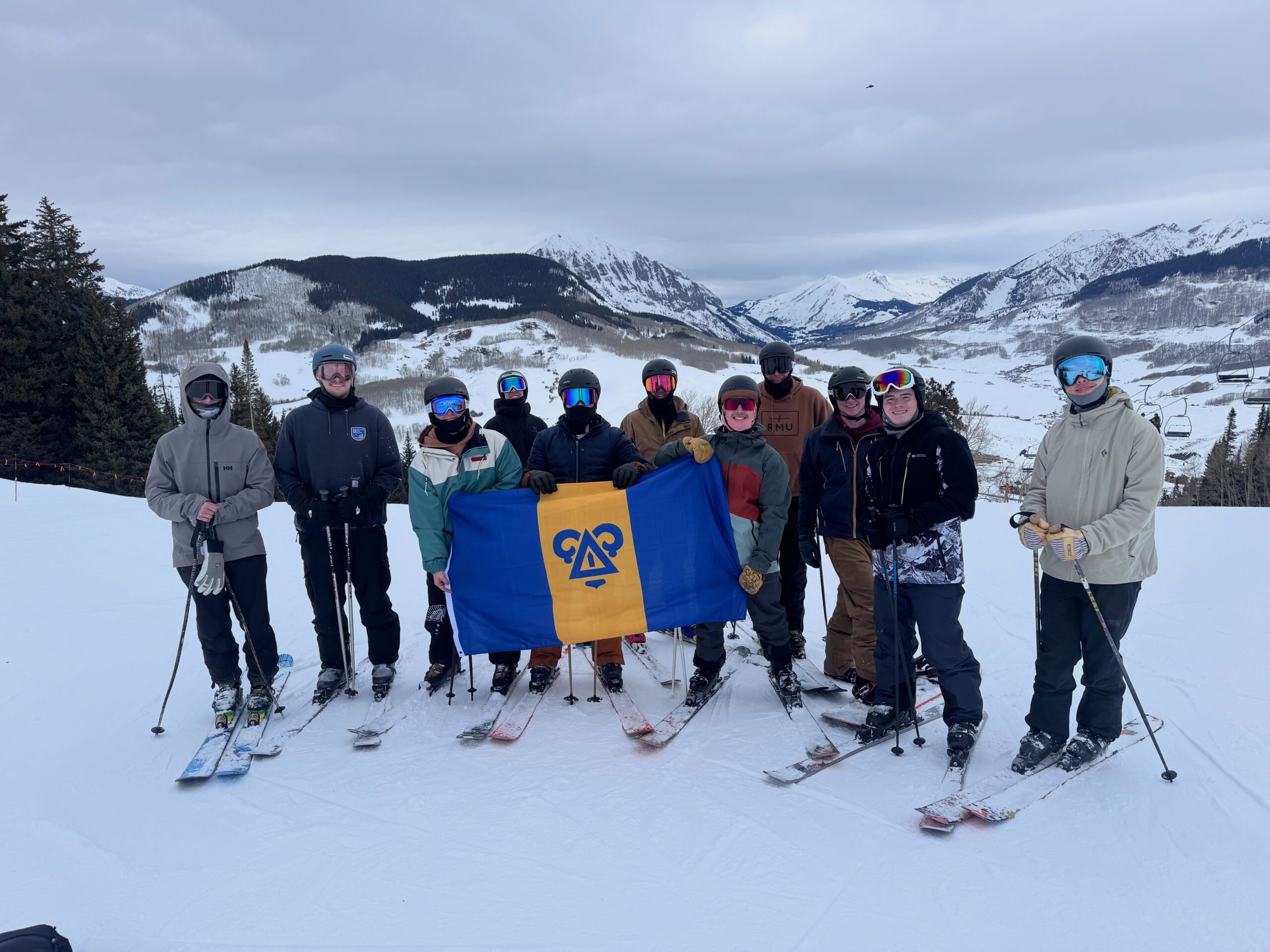 Delta Upsilon members pose with their flag on the CBMR ski resort.