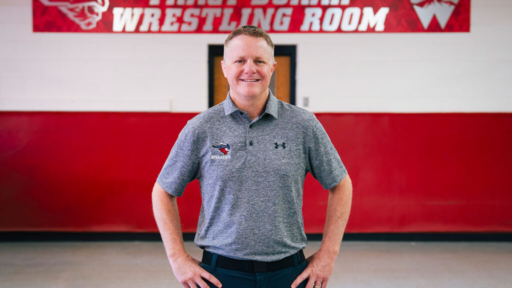 Van Hee poses in front of the Wrestling locker room.