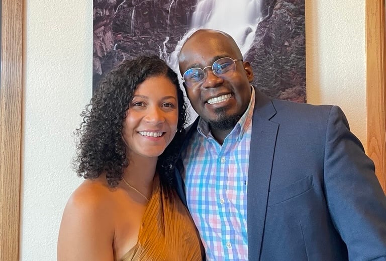 Jermaine poses with his partner in front of a painting.