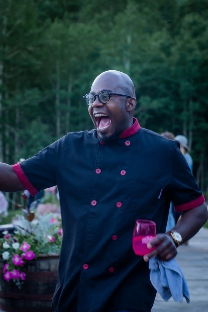 Jermaine laughing in his chef coat at an outdoor event.